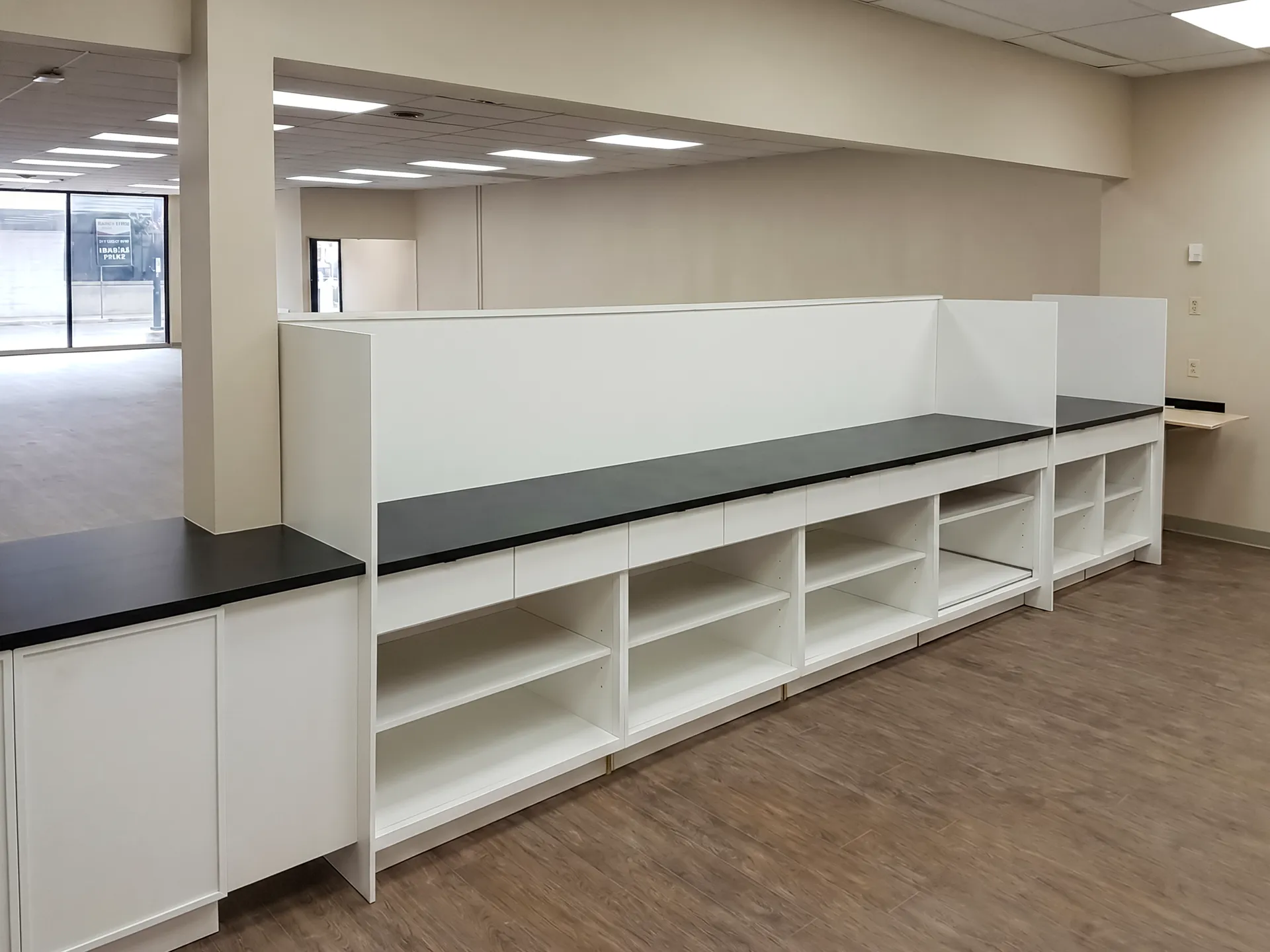 Dispensary bench with black laminate top, drawers, and open adjustable shelving