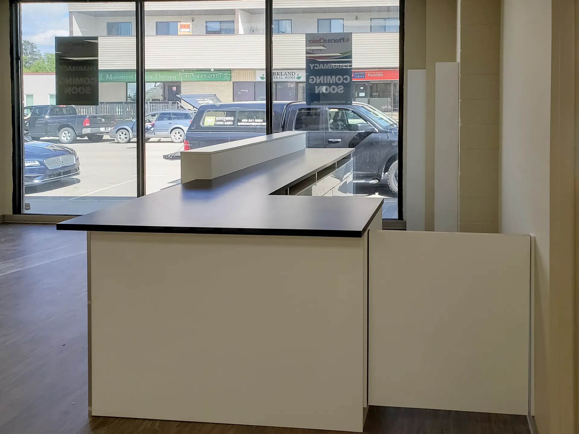 L shaped pharmacy pickup counter with lowered transaction ledge at the storefront window